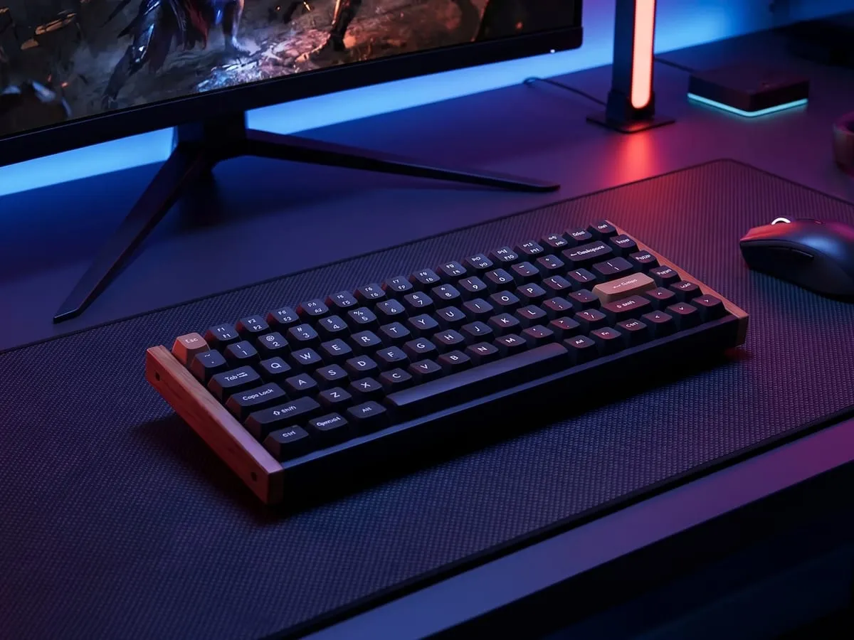 Keychron K2 HE on a dark gaming battlestation with cool blue and red ambient light, a curved monitor, and a wireless mouse