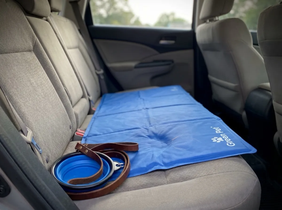 The Green Pet Shop cooling mat for dogs in a travel context — the blue pad shown ready for a shaded car backseat or crate