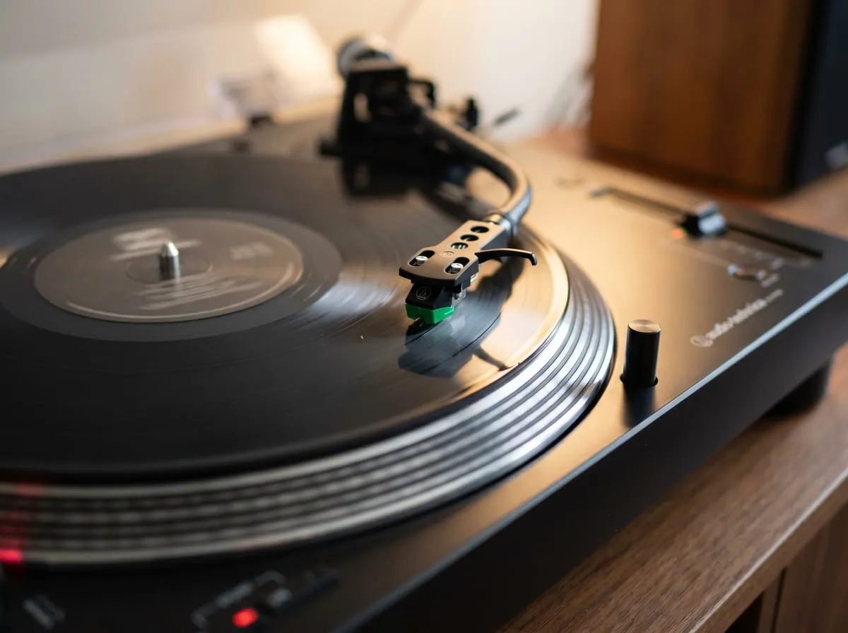 Close-up of the Audio-Technica AT-LP120XUSB tonearm, AT-VM95E cartridge and pitch control with a record on the platter